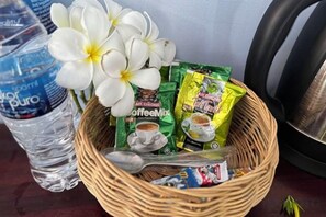 A wicker basket containing coffee packets, a spoon, and a water bottle. - Hawaii Lounge (Sihanoukville)
