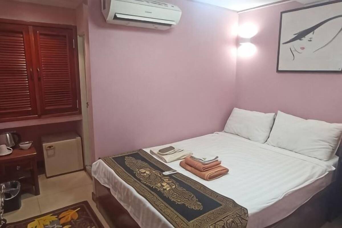 Une chambre comprenant un lit, une armoire, un petit coin cuisine et un appareil de climatisation.