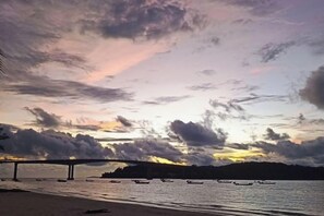 A sunset over a body of water with a bridge and boats. - Hawaii Lounge (Sihanoukville)