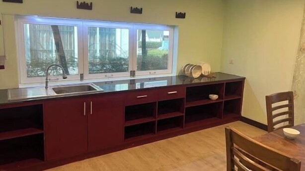 A kitchen with a large window, a sink, and a dining area with chairs. - Hawaii Lounge (Sihanoukville)