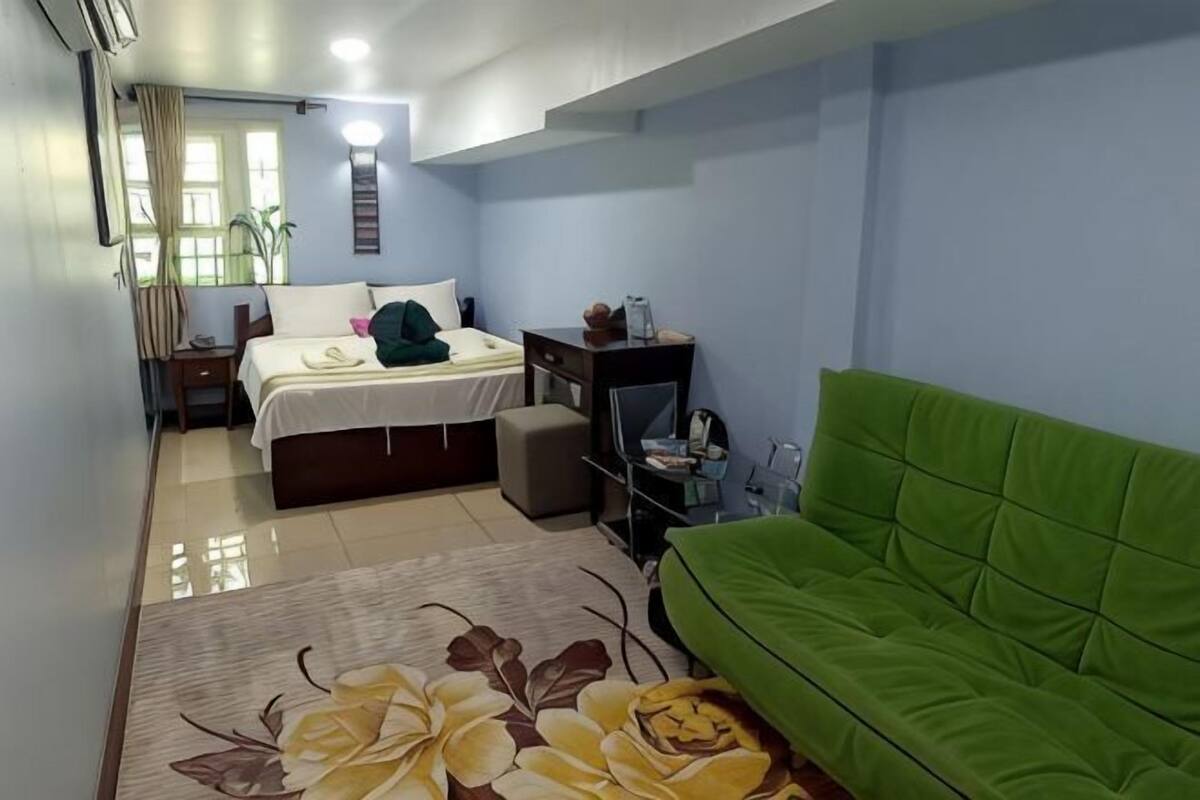 Une chambre avec un lit, un canapé vert, un bureau et une petite table.