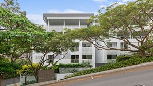 A modern building with a flat roof and a balcony on the second floor. - 2-bed Getaway With Shared Pool & BBQ Access (Brisbane)