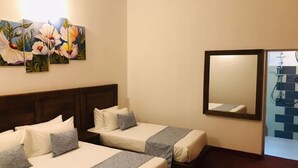 Een hotelkamer met twee bedden, een grote spiegel en een bloemenstilleven aan de muur.