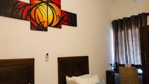 Een hotelkamer met twee bedden, een nachtkastje, een stoel en een kunstwerk aan de muur.