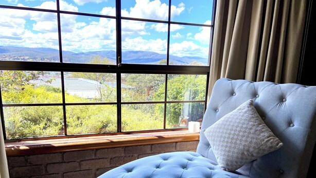 A room with a large window offering a view of a landscape with trees and distant buildings. - Marvelous 4-bedroom house in Moonah (Moonah)