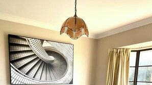 A bedroom with a large bed, a wall-mounted artwork, a window with curtains, and a hanging light fixture. - Marvelous 4-bedroom house in Moonah (Moonah)