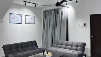 A modern living room with two sofas, a coffee table, and a ceiling fan.