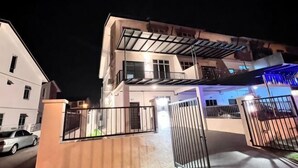 A multi-story building with a gated entrance, a covered outdoor area, and a visible balcony. - Senai 14pax The Joyous Home Pooltable Airport JPO (Senai)