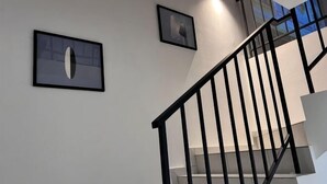 A staircase with a black railing, white walls, and two framed pictures. - Senai 14pax The Joyous Home Pooltable Airport JPO (Senai)