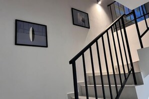 A staircase with a black railing, white walls, and two framed pictures. - Senai 14pax The Joyous Home Pooltable Airport JPO (Senai)
