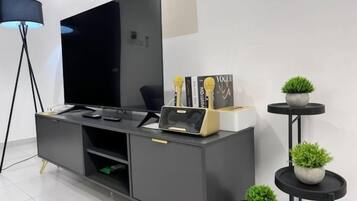 Ein modernes Wohnzimmer mit Flachbildfernseher, einer Couch, einem Couchtisch und einer Stehlampe.