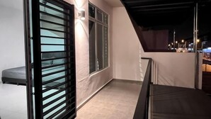 A balcony with a glass door, a bed, and a view of the city at night. - Senai 14pax The Joyous Home Pooltable Airport JPO (Senai)