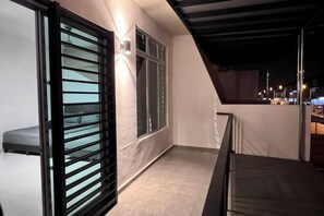 A balcony with a glass door, a bed, and a view of the city at night. - Senai 14pax The Joyous Home Pooltable Airport JPO (Senai)