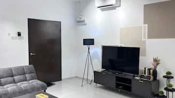 En moderne stue med sofa, fladskærms-tv, sofabord og et sort tv-møbel.