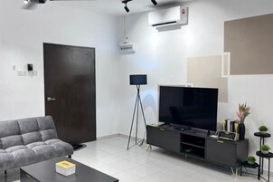 A modern living room with a sofa, a flat-screen TV, a coffee table, and a black entertainment unit.
