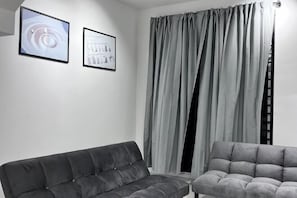 A room with a grey sofa, a grey armchair, and two framed pictures on the wall. - Senai 14pax The Joyous Home Pooltable Airport JPO (Senai)