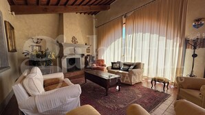 A living room with a fireplace, a sofa set, a coffee table, and a patterned rug. - La Casa degli Archi (Cevoli)