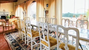 A dining area with a long table, white chairs, and a patterned rug. - La Casa degli Archi (Cevoli)
