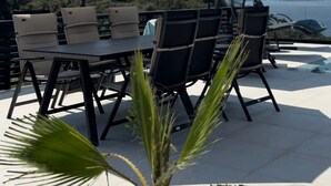 An outdoor patio with a table and chairs, two umbrellas, and a view of the sea. - Cozy accommodation with stunning sea views and everything around is incomparable to see. (Utjeha-Bušat)