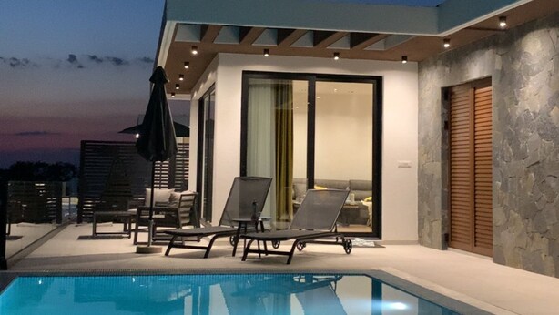 A modern outdoor pool area with lounge chairs and a glass-enclosed patio. - Cozy accommodation with stunning sea views and everything around is incomparable to see. (Utjeha-Bušat)