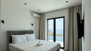 A modern bedroom with a large bed, a TV mounted on the wall, and a view of the sea through the window. - Cozy accommodation with stunning sea views and everything around is incomparable to see. (Utjeha-Bušat)