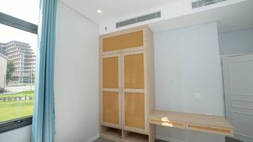 A modern room with a built-in wardrobe, a small desk, and a window with a view of buildings and greenery.