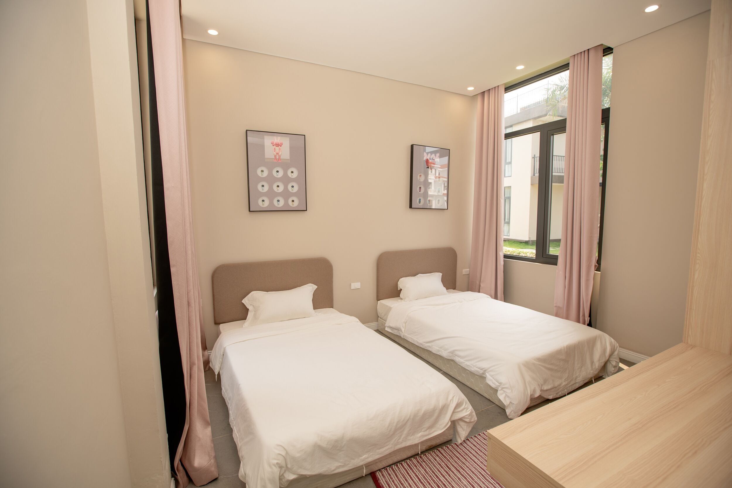 Une chambre d’hôtel avec deux lits, un bureau en bois et une fenêtre avec des rideaux.