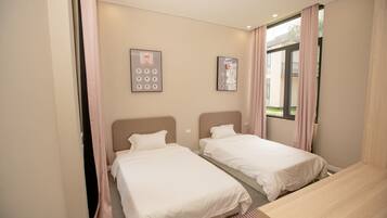 Une chambre d’hôtel avec deux lits, un bureau en bois et une fenêtre avec des rideaux.