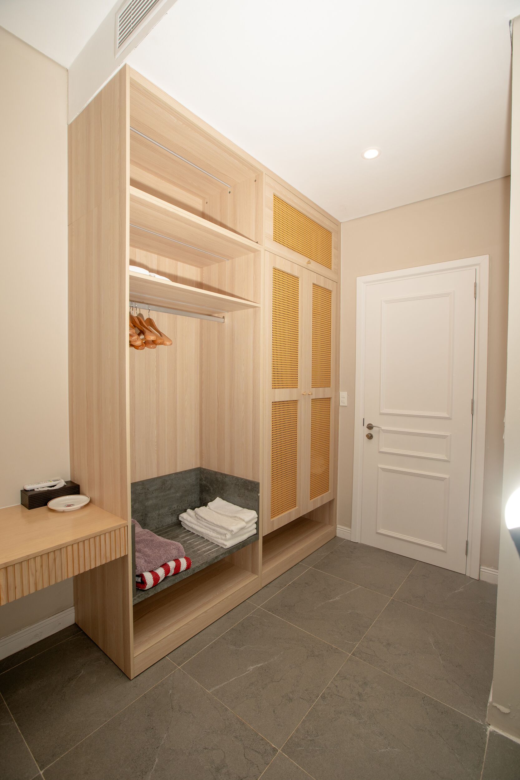 A walk-in closet with wooden shelving, a bench, and a door.