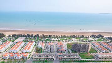 An aerial view of a coastal residential area with multiple apartment complexes, a beach, and a clear view of the ocean.