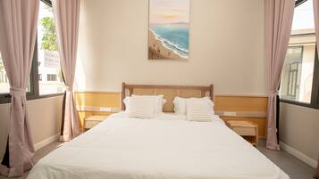 A hotel room with a large bed, two bedside tables, a headboard, and a painting of a beach scene.