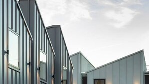 A modern building with a series of vertical windows and a wooden fence in the foreground. - Spacious Central Townhouse – Perfect for All (Christchurch)