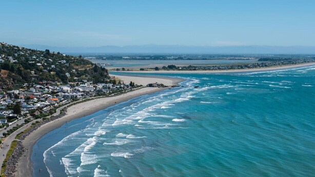 An aerial view of a coastal town with a beach, houses, and a hilly landscape. - Spacious Central Townhouse – Perfect for All (Christchurch)