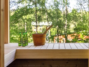 A wooden bench with three bottles of Heineken beer and a wooden bucket with a spoon.