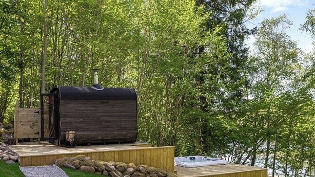 A sauna with a wooden exterior, a hot tub, and a wooden deck leading to the sauna. - Leas Pärla by Interhome (Torup)