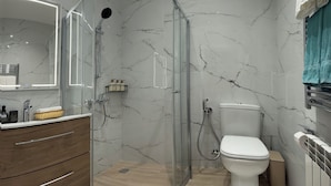 A modern bathroom with a glass-enclosed shower, a wooden vanity with a mirror, a toilet, and a towel rack. - MK Luxury Serviced Apartments #3 - Apt. 1 (Chișinău)