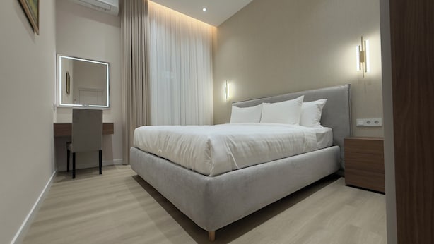 A modern bedroom with a large bed, a desk, and a chair. - MK Luxury Serviced Apartments #3 - Apt. 1 (Chișinău)