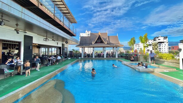 Une piscine extérieure dotée d’un espace de repos couvert et d’un restaurant situé sur un côté.