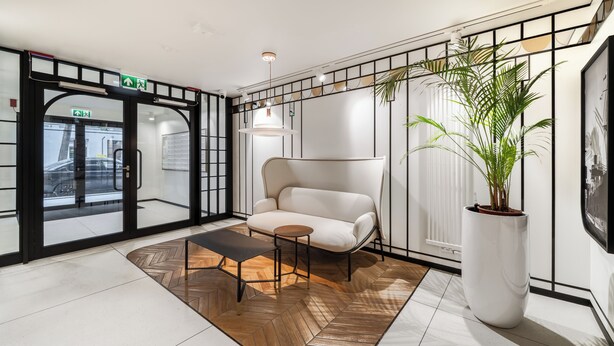 Un hall moderno con un sofá, una mesa de centro y una planta grande en maceta.