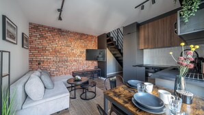 Una cocina moderna con pared de ladrillo, un comedor con mesa de madera y una escalera.