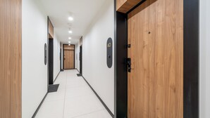 Un pasillo con puertas de madera, placas de número en cada puerta y suelo de baldosas.
