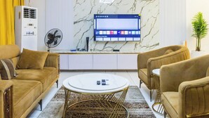 Een moderne woonkamer met een marmeren wand, een flatscreen televisie en een salontafel in het midden.