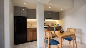 Una cocina moderna con un refrigerador negro, armarios de madera y un comedor con una mesa de madera y dos sillas.