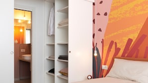 A bedroom with a bed, a nightstand, a wall-mounted lamp, and a wardrobe with shelves. - 7Studios - 4 orange (Milano)