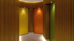 A hallway with three doors, each with a different color: yellow, orange, and green. - 7Studios - 4 orange (Milano)
