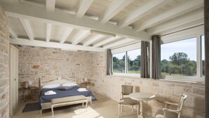 A bedroom with a stone wall, a bed, a bench, a table, and chairs. - Villa Piccolo Paradiso with Heated Pool, Jacuzzi & Sauna (Rovinjsko Selo)