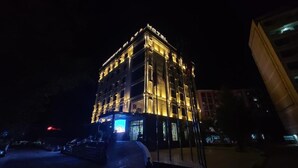 Un edificio de varios pisos con ventanas iluminadas y una entrada destacada.