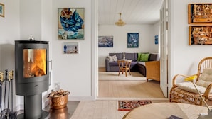 Un salon moderne avec un poêle à bois, un canapé et un coin repas.