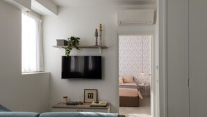 A modern living room with a flat-screen TV, a small table with books and a plant, and a sofa. - 7Studios - 1 Sage (Milano)