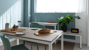 A dining area with a table set for two, a loaf of bread, a bowl of nuts, and a potted plant. - 7Studios - 1 Sage (Milano)